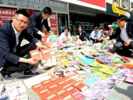 Law enforcement staff show copies of pirated dictionaries, textbooks and teaching materials confiscated at a cultural market in Huainan, Anhui province, Apr. 24, 2017. (Photo from People’s Daily Online)